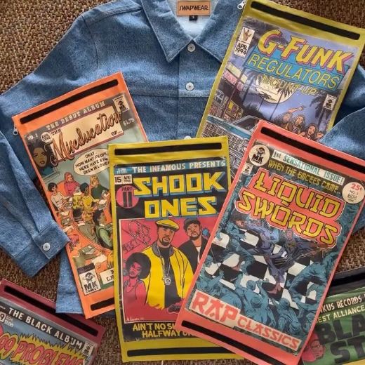Collection of MK COMICS comic book-style album covers on a SWAPWEAR denim shirt with sneakers visible.