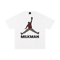 A white short-sleeve crewneck t-shirt featuring a graphic of Colton Cowser in orange and black orioles jersey mid-homerun rob, with the word 'MILKMAN' printed in bold black letters underneath.